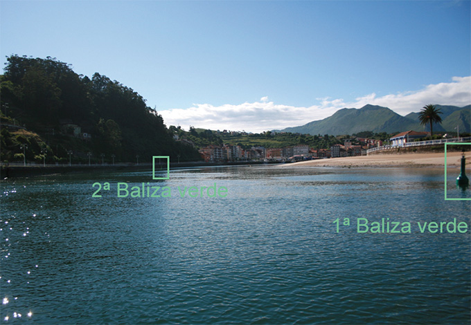 Y dos boyas cilíndricas verdes en la ribera de la playa 