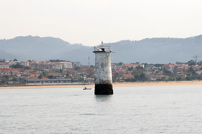 Baliza del Pego de San Xoán. Al fondo Playa América